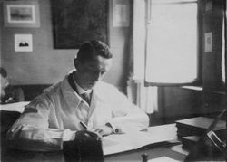 Mann im weißen Kittel am Schreibtisch, 1920er