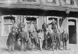 Männergruppe vor Werkstatt oder Geschäft, Raum Saarbrücken, wohl 1890er