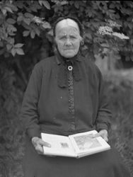 Ältere Frau mit Buch im Garten, wohl 1930er