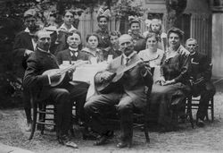 Große Tischrunde mit Musikanten, wohl um 1900-1910